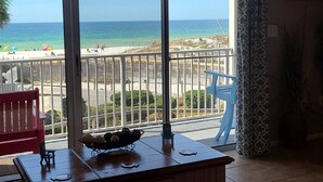 A balcony with a view of the beach, a table with a bowl of fruit, and a red chair. - The best beach views from condo of crystal white sand beach (Seagrove Beach)