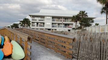 Walk along the boardwalk to our beachfront property, featuring a multi-story building with balconies.