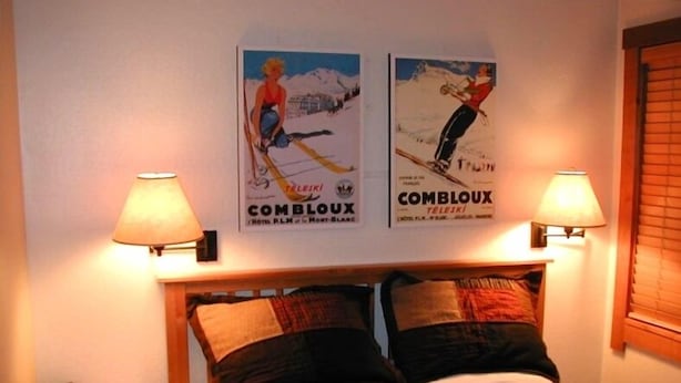A bed with two pillows, a bedside table, and two wall-mounted lamps.