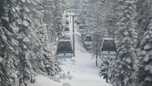 A snow-covered ski lift with cabins, surrounded by snow-laden trees.