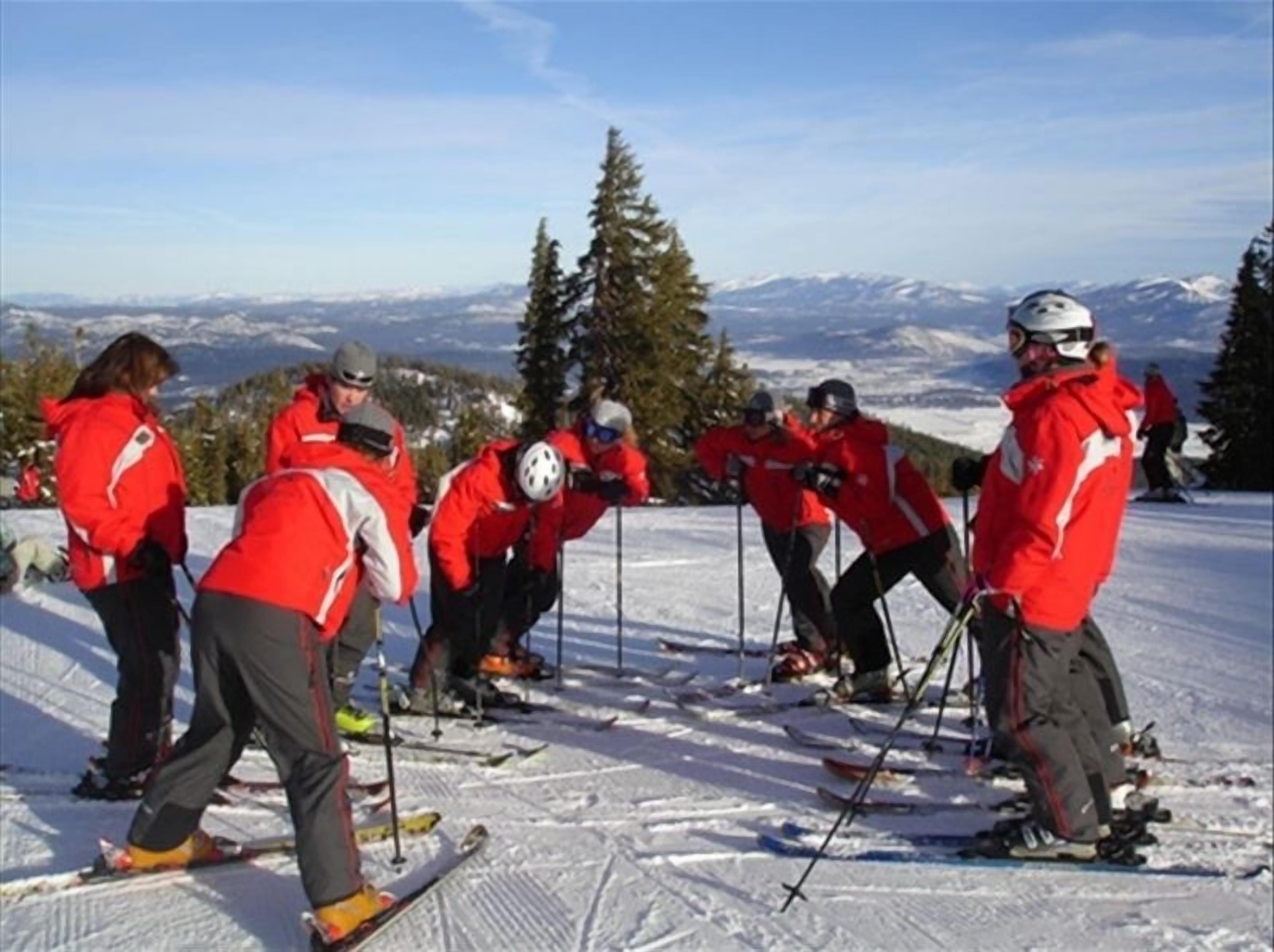 A group of people skiing on a snowy slope with a mountainous backdrop.