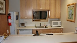 A compact kitchen with wooden cabinets, a microwave, a toaster, and a sink.