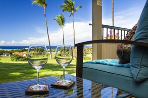 A glass table with two wine glasses and a view of a golf course and ocean. - You'll Love The Ocean Views! 5 Star Hospitality! Hoʻokipa at Wailea Ekolu. (Wailea)