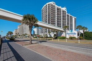 Un hôtel situé en bord de mer, reconnaissable à son grand panneau « Surfside », doté de nombreux balcons et d’une promenade piétonne.
