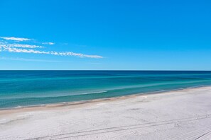 Une plage avec une eau d’un bleu limpide et un rivage sablonneux.