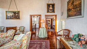 Una habitación amplia con sofás de estampado floral, una mesa de centro de madera y un cuadro grande en la pared.