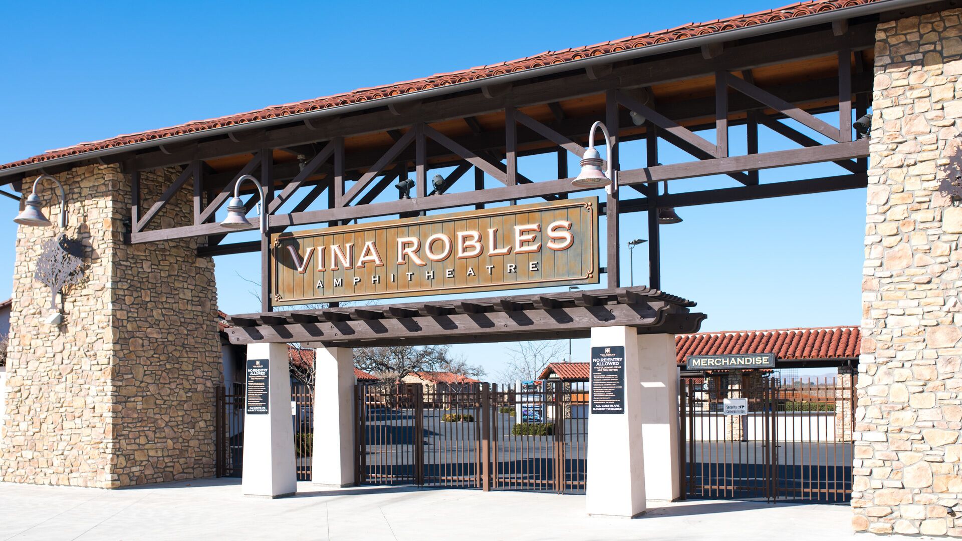 A sign for Vina Robles Amphitheatre with a metal gate and stone walls.
