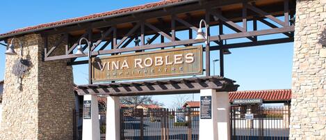 A sign for Vina Robles Amphitheatre with a metal gate and stone walls.
