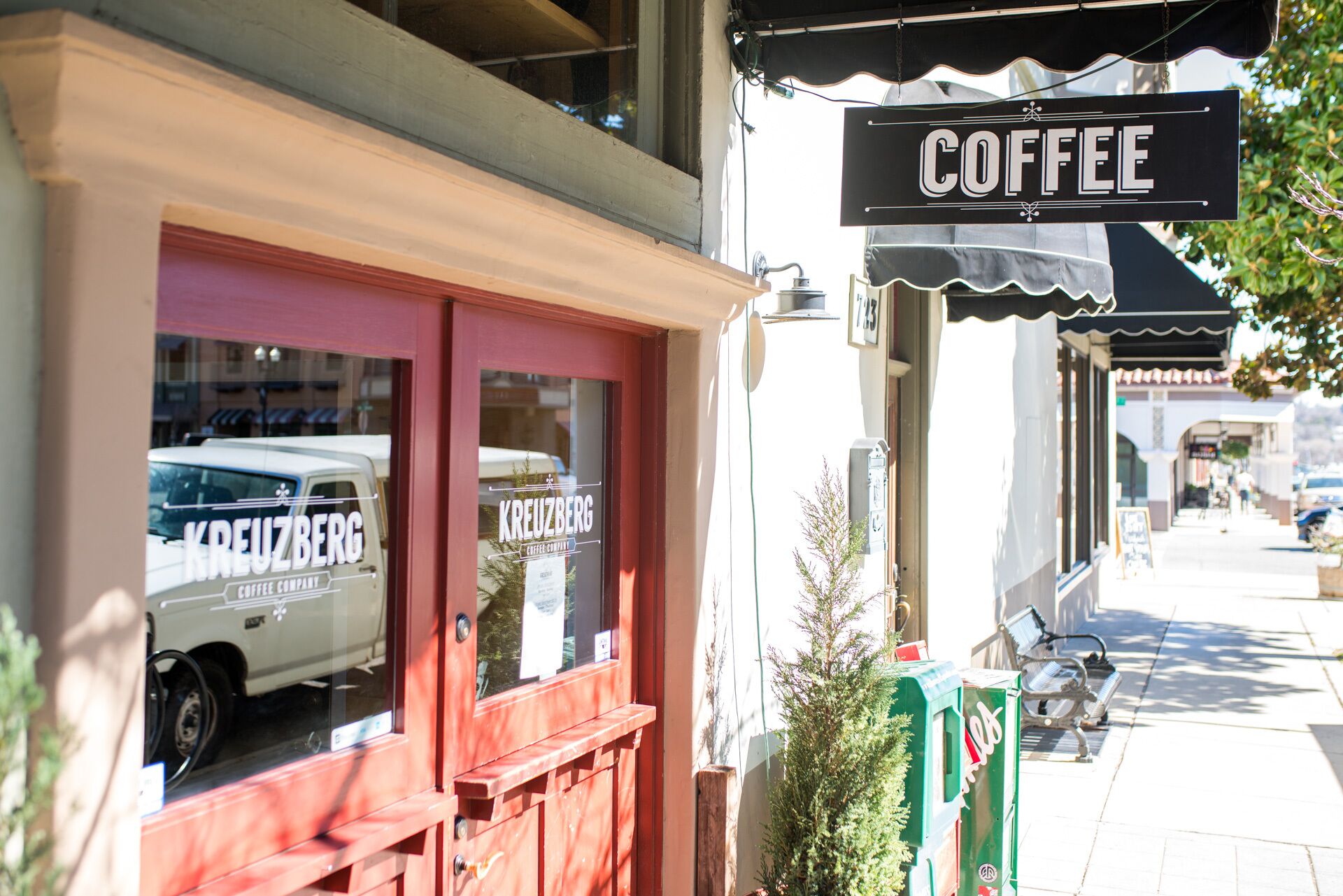 A storefront with a 'Coffee' sign, a red door, and a parked van outside.