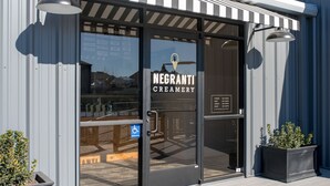 The exterior of Negranti Creamery with a clear glass door, a handicap accessible sign, and a metal awning.