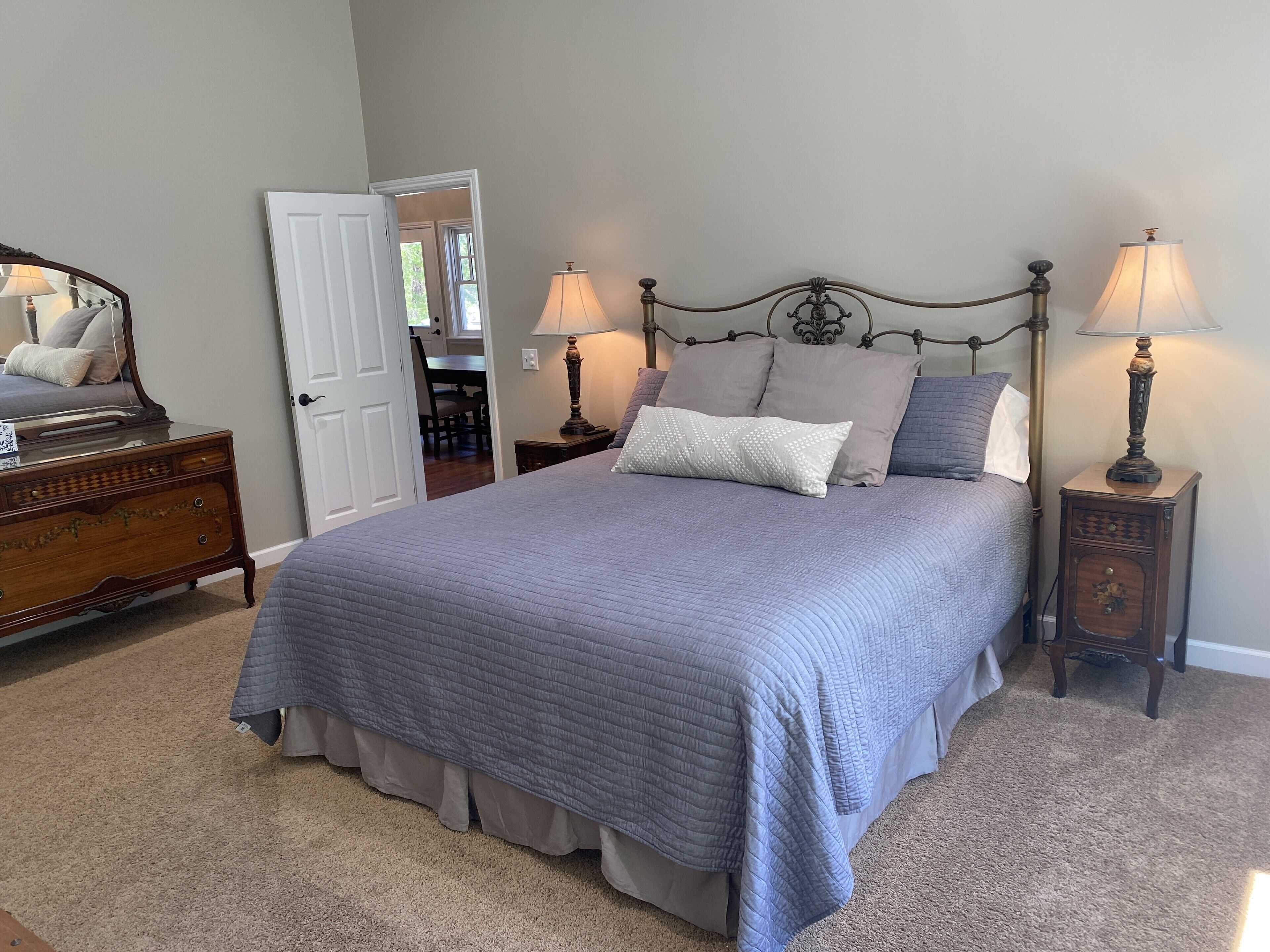 Une chambre à coucher avec un lit, deux tables de chevet avec des lampes, une commode et un miroir.