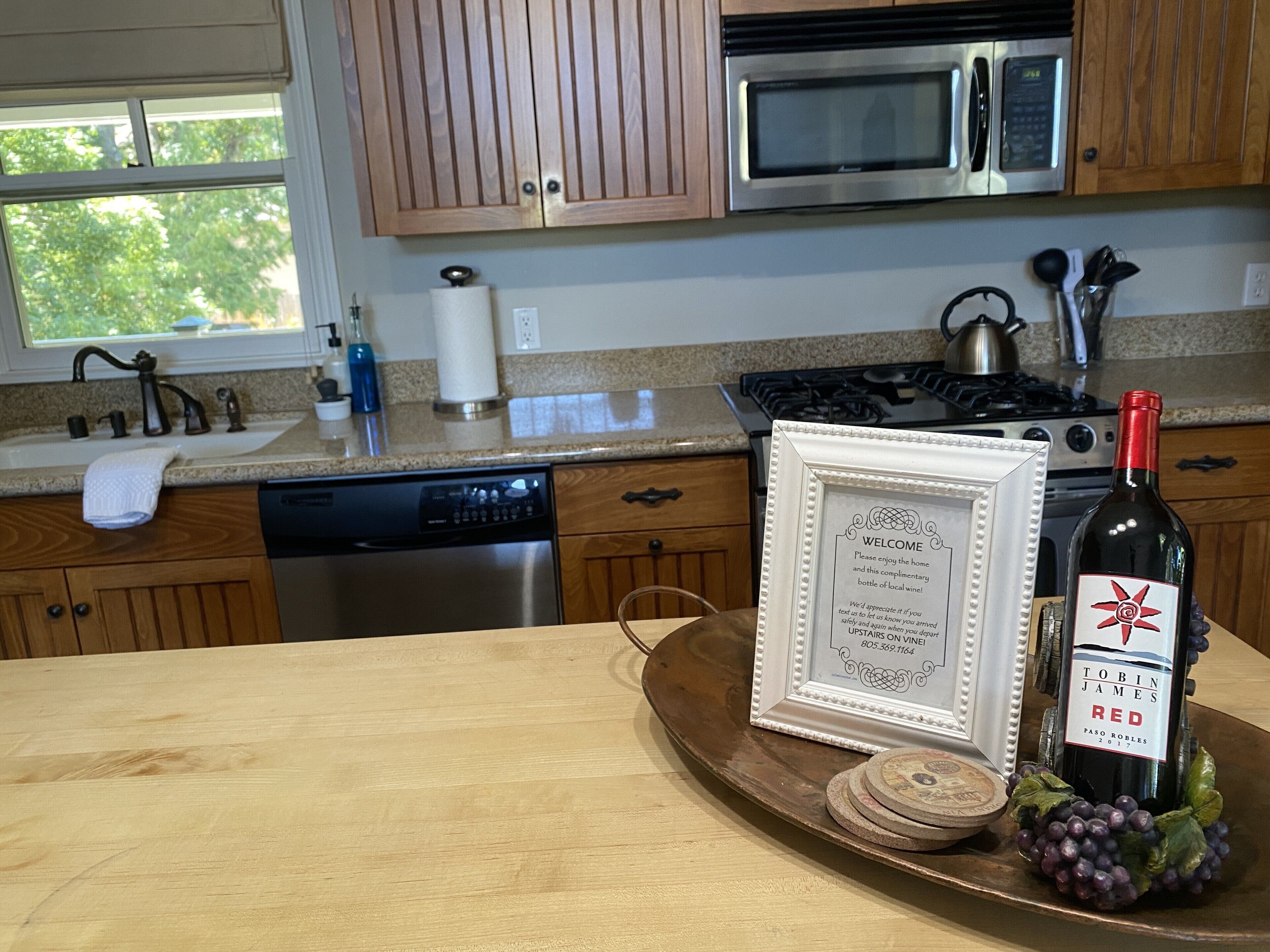 A kitchen with wooden cabinets, stainless steel appliances, and a framed welcome sign on the counter.
