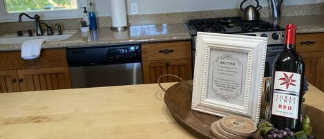 A kitchen with wooden cabinets, stainless steel appliances, and a framed welcome sign on the counter.