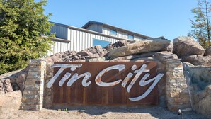 A sign with the name "Tin City" in large letters, surrounded by rocks and a stone wall.