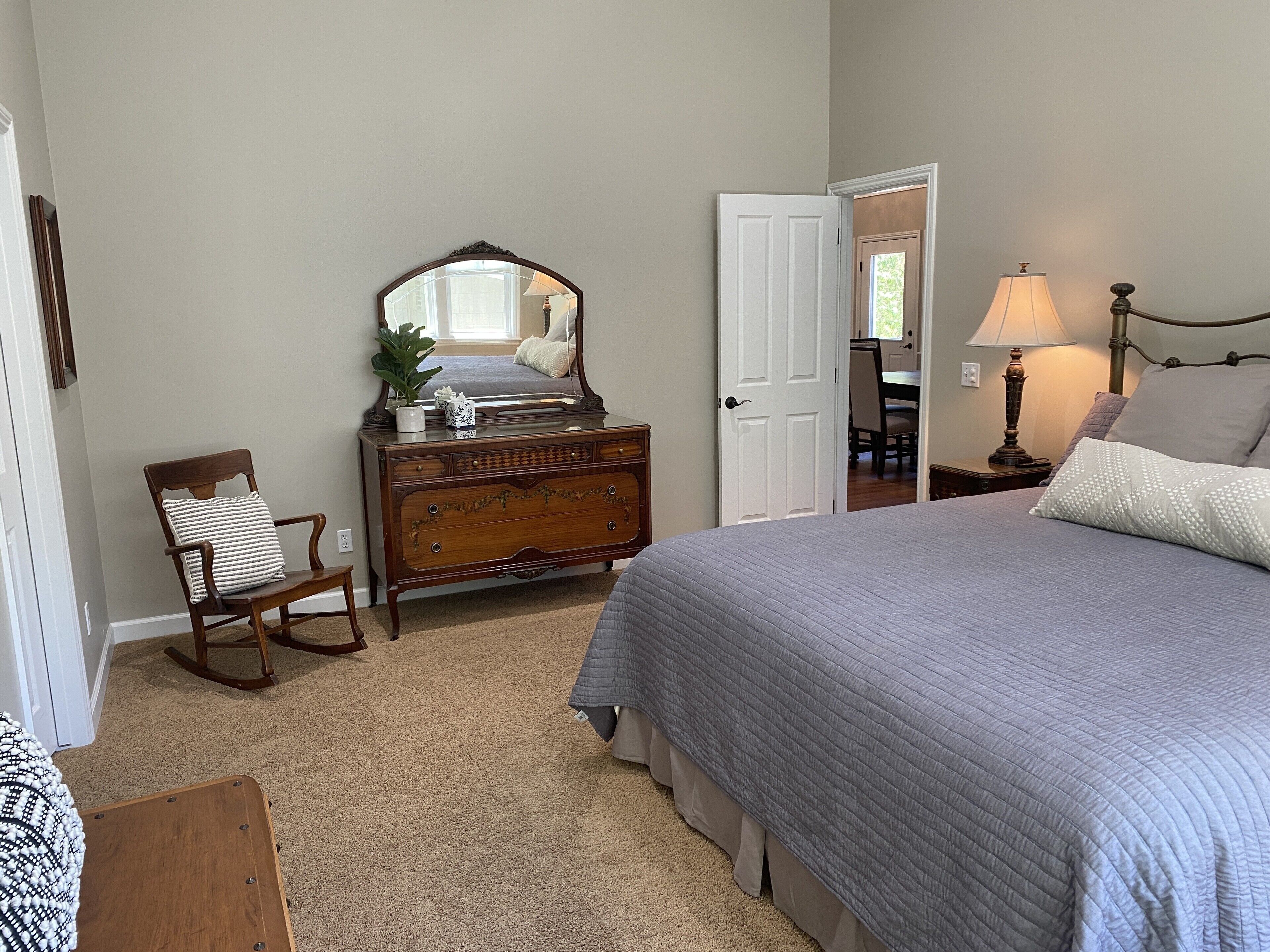 Une chambre à coucher avec un lit, une commode, une chaise et un miroir.