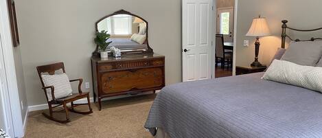 Une chambre à coucher avec un lit, une commode, une chaise et un miroir.