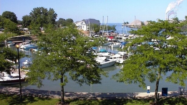 Un port de plaisance avec des bateaux amarrés, entouré d’arbres et avec un bâtiment visible au loin.