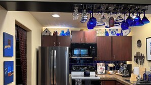 Een moderne keuken met roestvrijstalen apparatuur, een granieten aanrechtblad en decoratief blauw glaswerk.