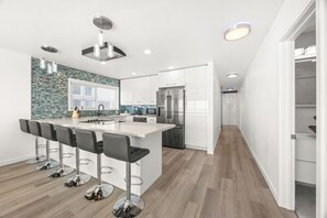 A modern kitchen with a central island, bar stools, and a backsplash.
