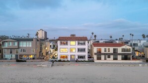 Una zona residenziale sul lungomare con case moderne, una spiaggia sabbiosa e palme.