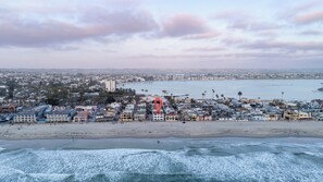 A coastal cityscape with a beach, buildings, and a red landmark.