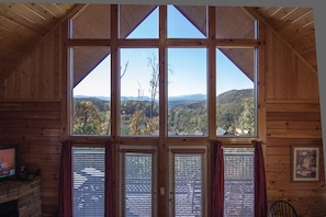 Enjoy a forest view from the large window, with a fireplace and TV for a cozy atmosphere.