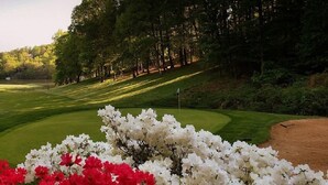Un campo de golf con un fairway bien cuidado, búnkeres de arena y un club house.