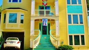 A two-story house with a front porch, a garage, and a staircase leading to the entrance. - TIKI POOL & SPA, GOLF CART, KAYAK, WATERFALL, FIREPIT EXCELLENT LIGHTHOUSE VIEWS (Corolla)