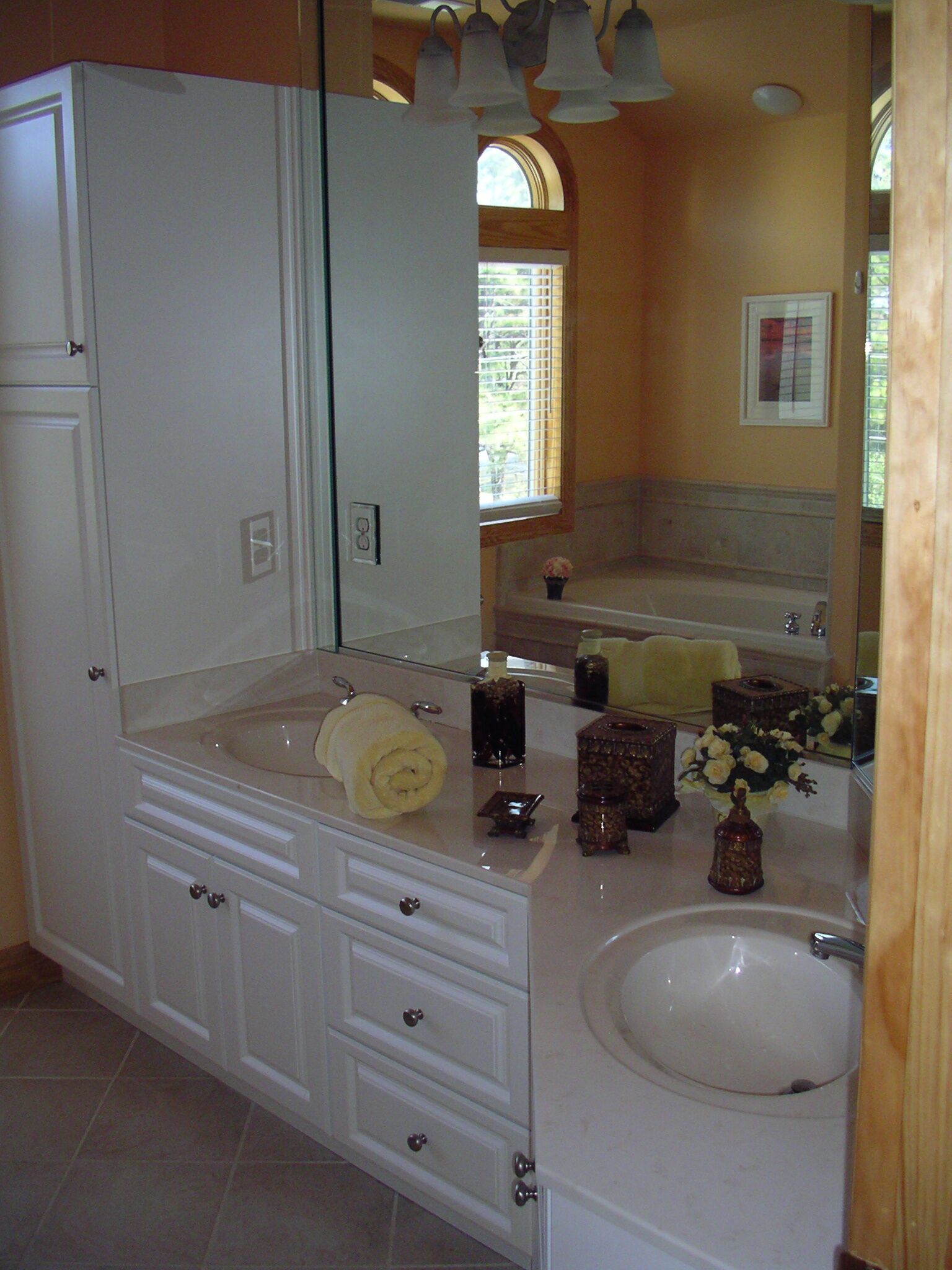Un baño con un espejo grande, un lavabo blanco y un mueble de tocador con cajones.
