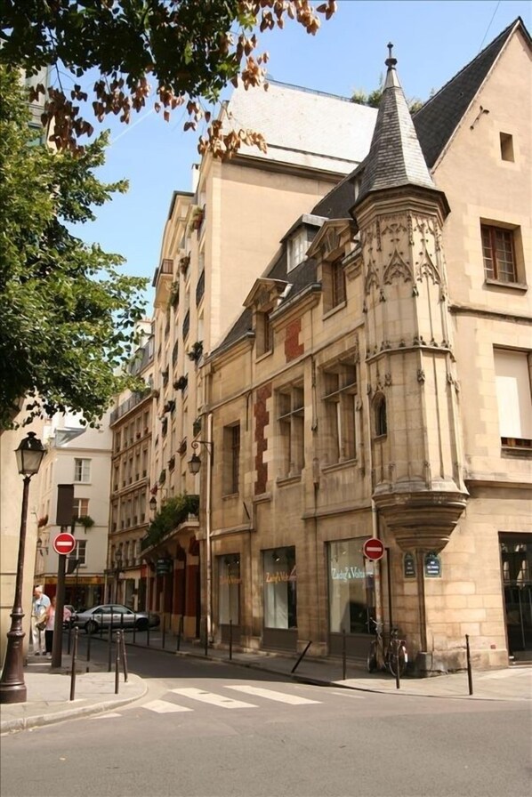 A historic building with a corner turret, a street with a 'no entry' sign, and a bicycle parked outside.