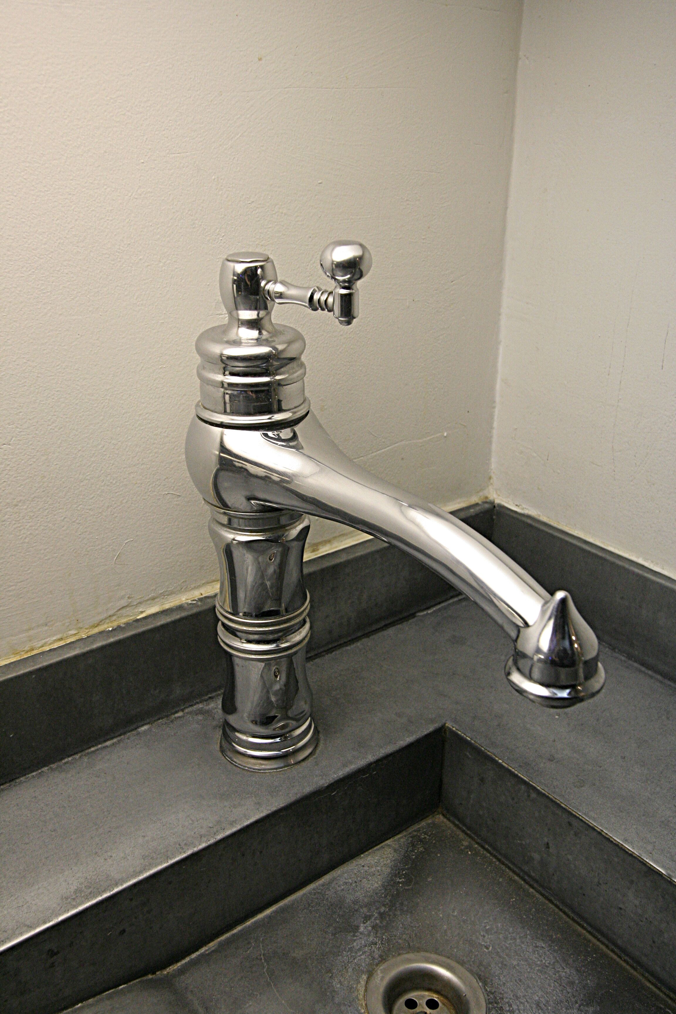 Rubinetto cromato con maniglia a leva e soffione estraibile separato, installato in un lavandino d'angolo con scarico.