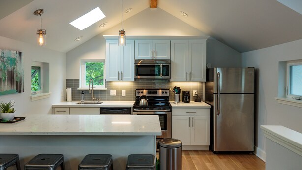 A modern kitchen with a large island, stainless steel appliances, and a skylight.