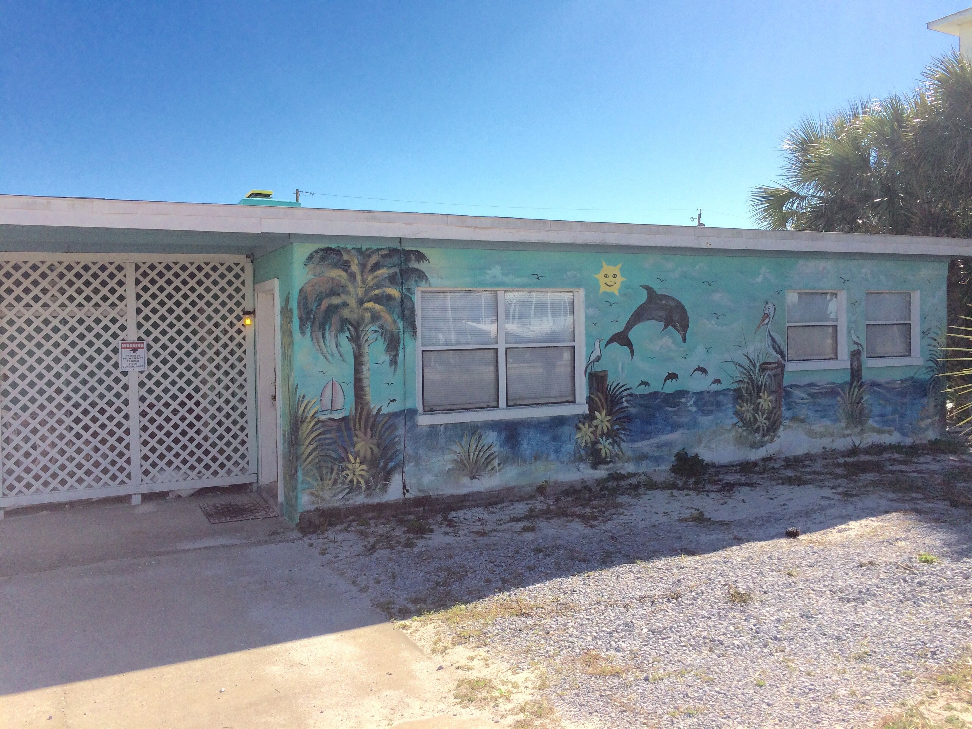 A building with a mural of marine life and a palm tree.