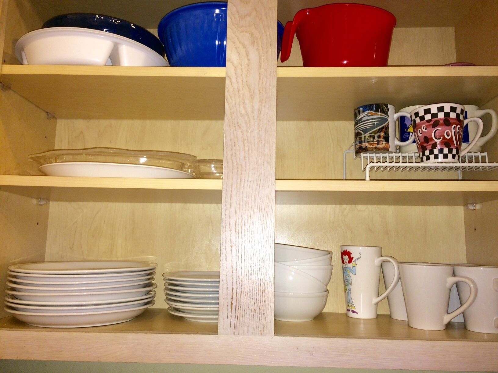 A kitchen shelf with various dishes and mugs.