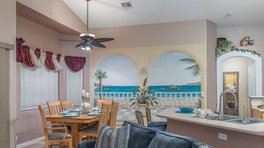Un comedor con vistas al mar, una cocina con lavamanos y un ventilador de techo.