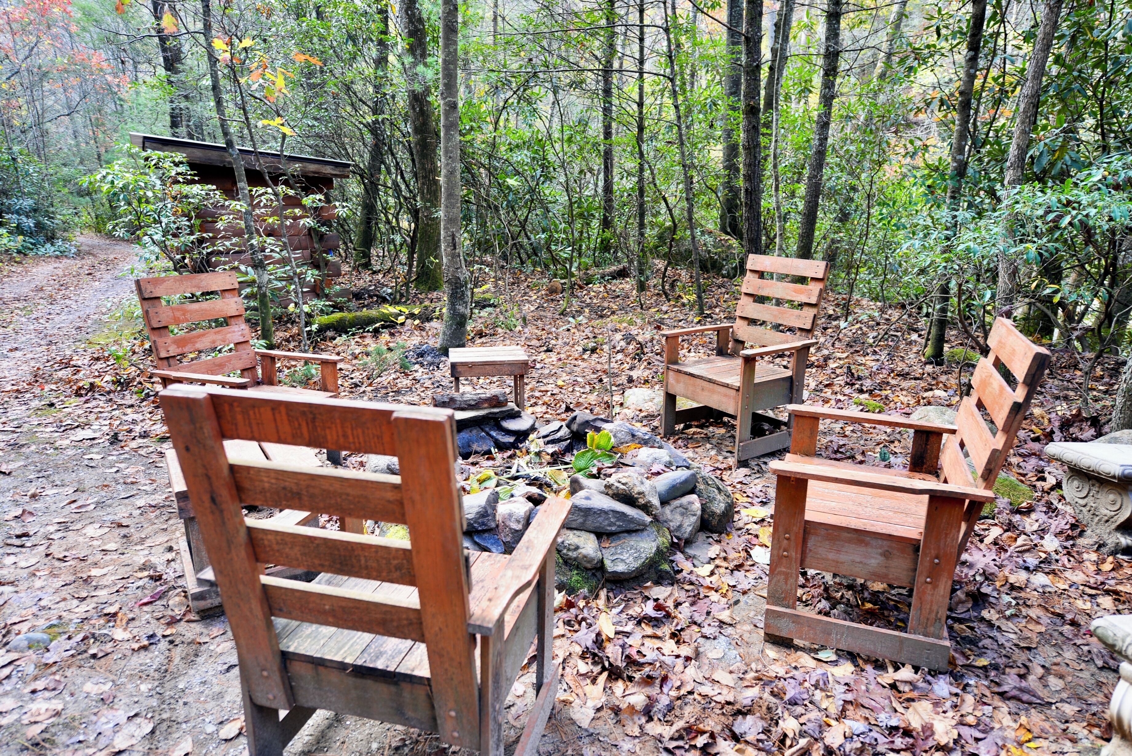 A rustic wooden bench seating area surrounded by rocks and trees in a forest setting.