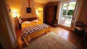 Une chambre à coucher avec un lit, une armoire en bois, une chaise et une grande fenêtre.