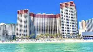 A large hotel with multiple floors, a beach in the foreground, and clear blue skies. - 🌴 Rare Double Gulf View~Free Beach Chairs~No Resort Fee~2nd floor Front Parking (Panama City Beach)