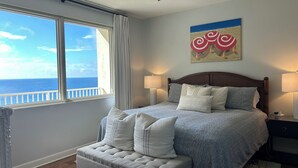 A bedroom with a bed, a nightstand, a lamp, a ceiling fan, a window with a view of the ocean, and a painting on the wall. - 🌴 Rare Double Gulf View~Free Beach Chairs~No Resort Fee~2nd floor Front Parking (Panama City Beach)