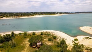 Un paisaje costero con una playa arenosa, aguas turquesas cristalinas y árboles dispersos.