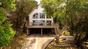 Una casa moderna con terraza, rodeada de árboles y un camino de piedra.