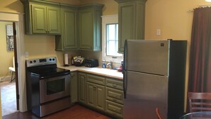 A kitchen with green cabinets, stainless steel appliances, and a wooden floor. - Tuscan Villa with Private Courtyard in Briarbrook (near Joplin Regional Airport) (Carl Junction)