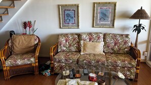 Een woonkamer met een bank, twee fauteuils, een salontafel en een trap.