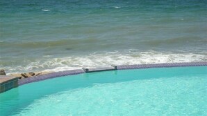 On peut clairement voir une piscine avec un bord carrelé, située à côté d’une étendue d’eau.
