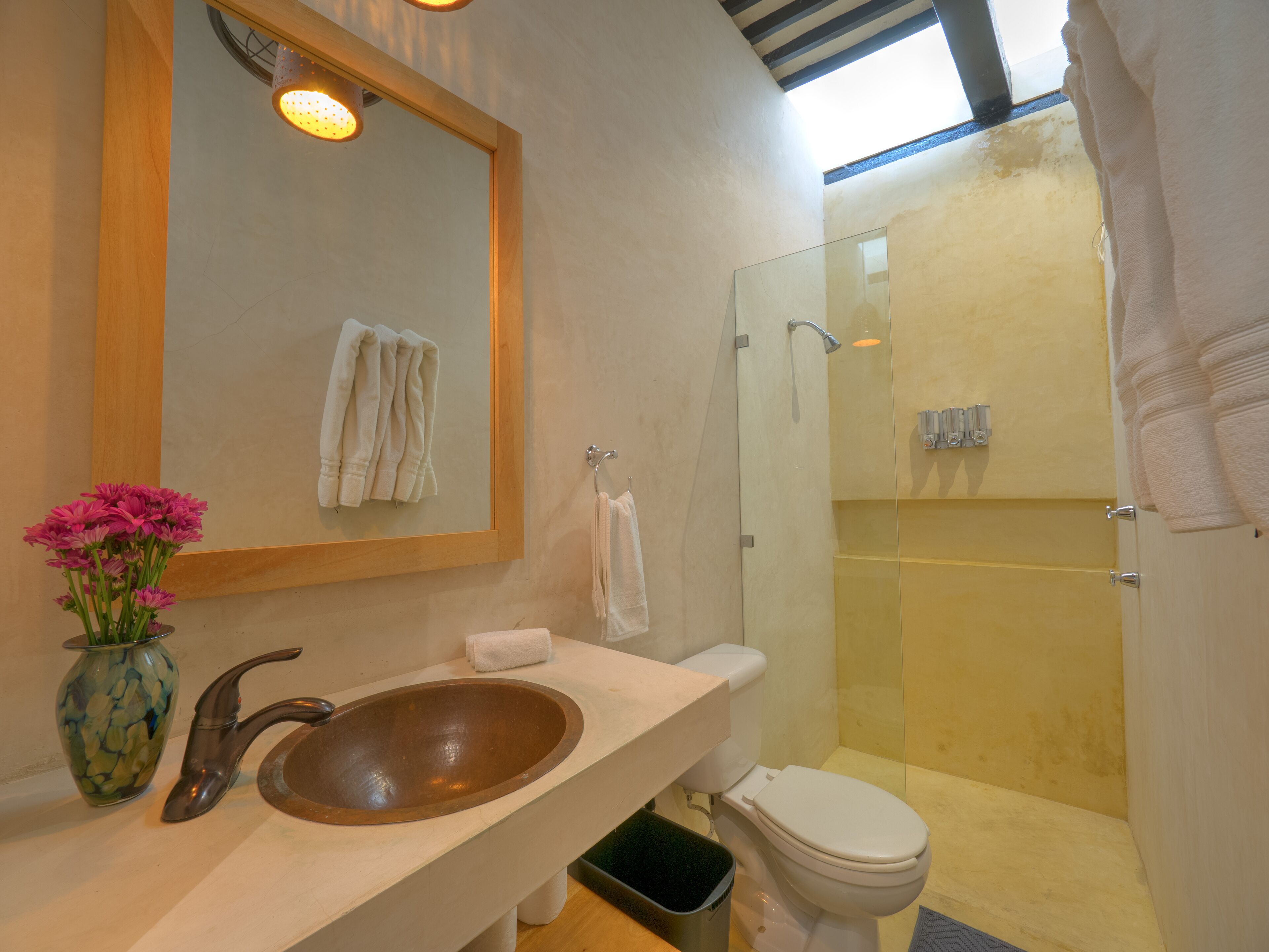Un baño con lavabo de madera, espejo y zona de ducha.