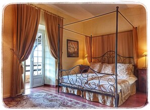 Una cama con dosel de estructura metálica, un tapete estampado y cortinas.
