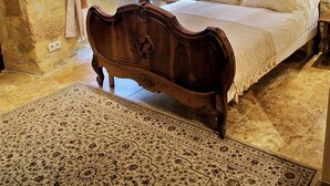 Une chambre à coucher avec un lit en bois, un lustre et un mur en pierre.