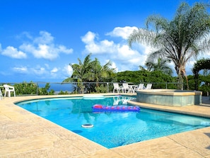 A swimming pool with clear blue water, surrounded by lounge chairs and palm trees. - Magnificent!  Private Pool & Hot Tub - 180 degree Ocean Views (Kailua Kona)