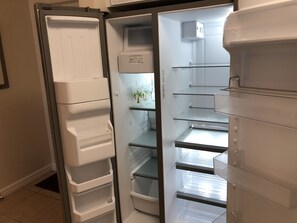 Geladeira aberta com várias prateleiras e um dispensador de água.