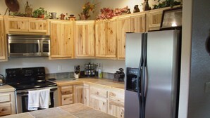 Una cocina con armarios de madera, un refrigerador de acero inoxidable, un microondas y una estufa.
